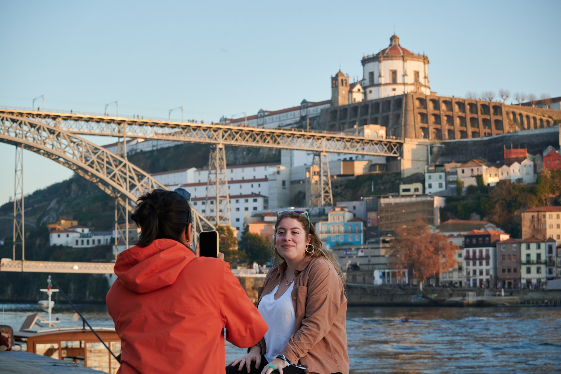 Una ragazza fotografa un’amica con un ponte di Porto sullo sfondo