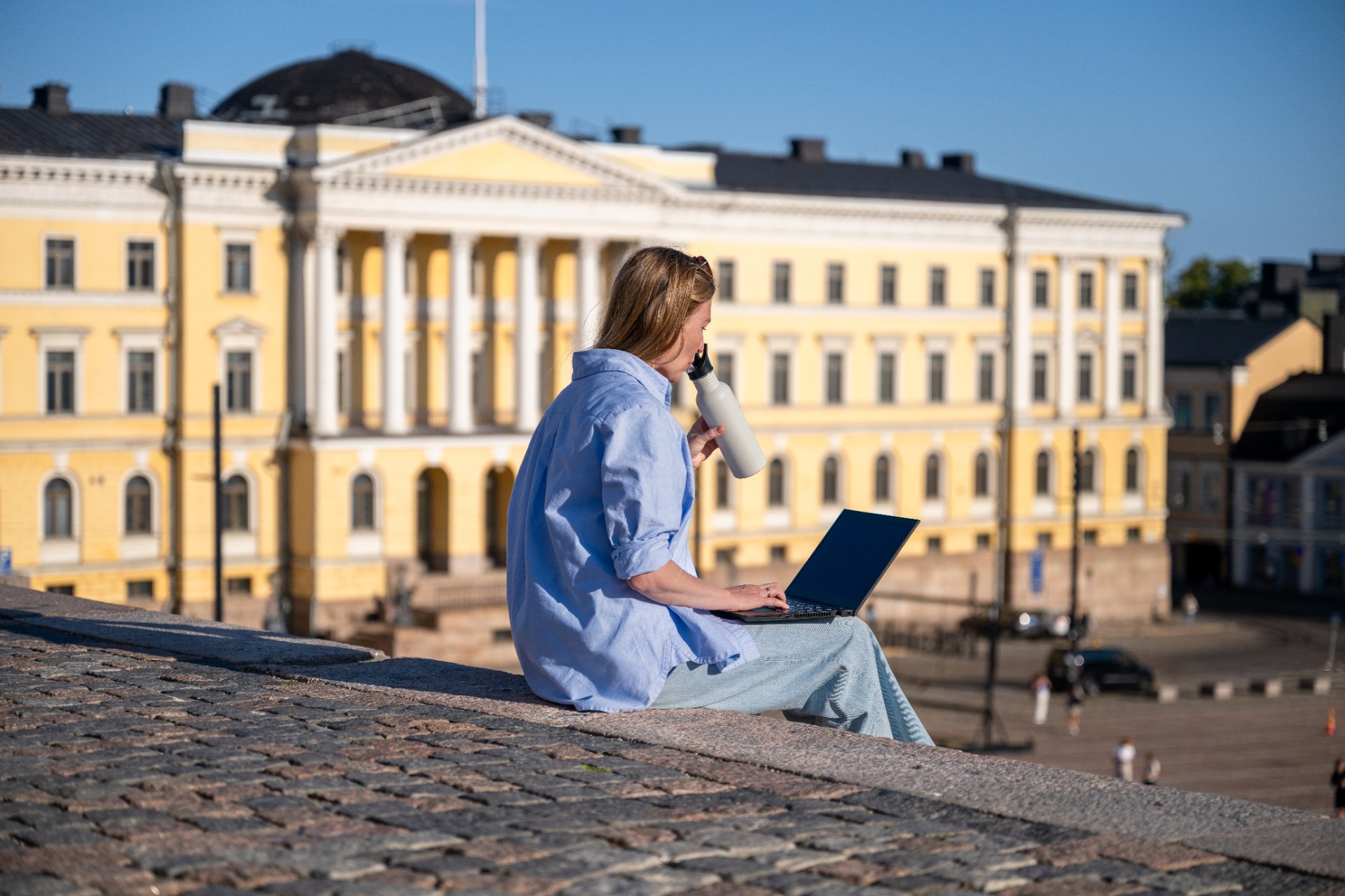 Ragazza con un portatile seduta sulla scalinata di Piazza del Senato a Helsinki