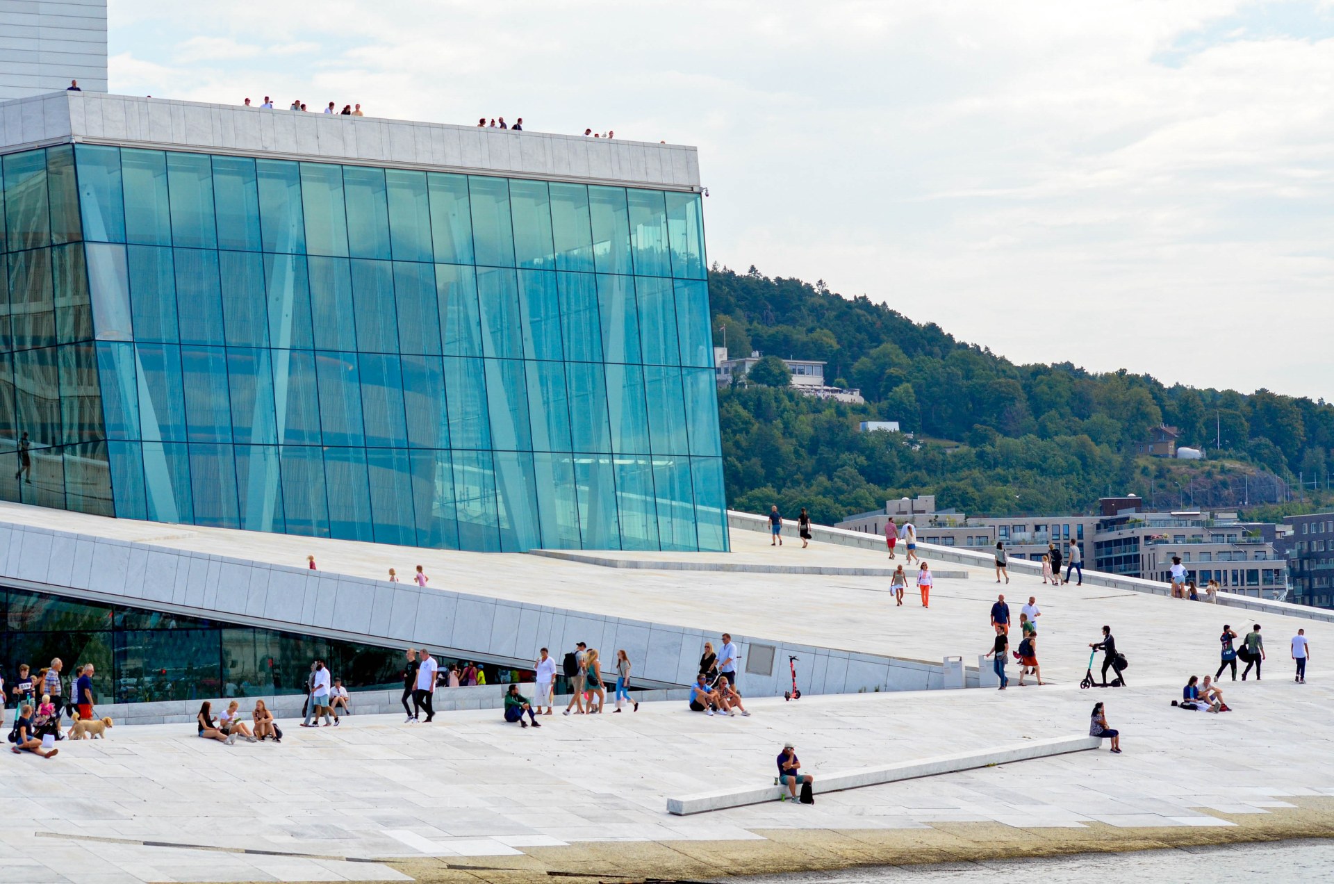 Persone che passeggiano e si rilassano sul tetto del Teatro dell’Opera di Oslo